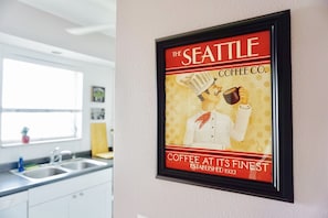 A framed coffee advertisement in a kitchen. - Cozy Family Apartment/2 miles to Ocean/Private BBQ/WiFi/Parking Free (Hollywood)