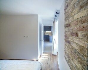A narrow hallway with a bed on the left and a brick wall on the right. - Emma central apartment (Porec)