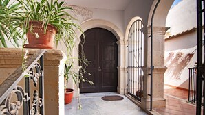 A courtyard with a dark wooden door, potted plants, and a tiled floor. - In Naca - Castello Maniace Ortigia Wifi (Siracusa)