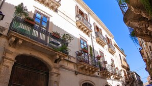 A historic building with ornate balconies, large wooden doors, and a clear blue sky. - In Naca - Castello Maniace Ortigia Wifi (Siracusa)