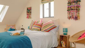 Un dormitorio con cama, ventana, mesita de noche, silla y un adorno en la pared.