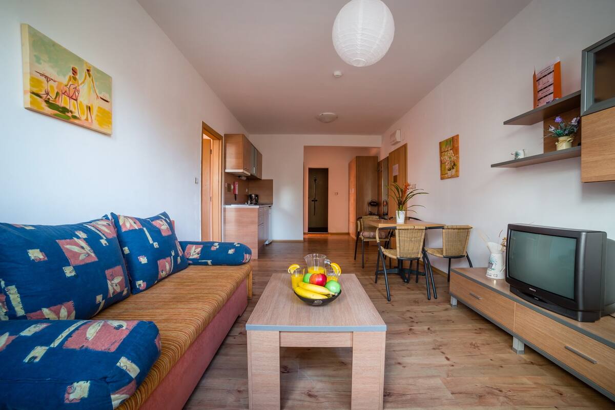 A living room with a sofa, coffee table, TV, and dining area.