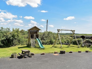 A playground with a slide, swing set, picnic table, and a small wooden structure. - Cider Cottage - UK11861 (Holsworthy, near Launceston)
