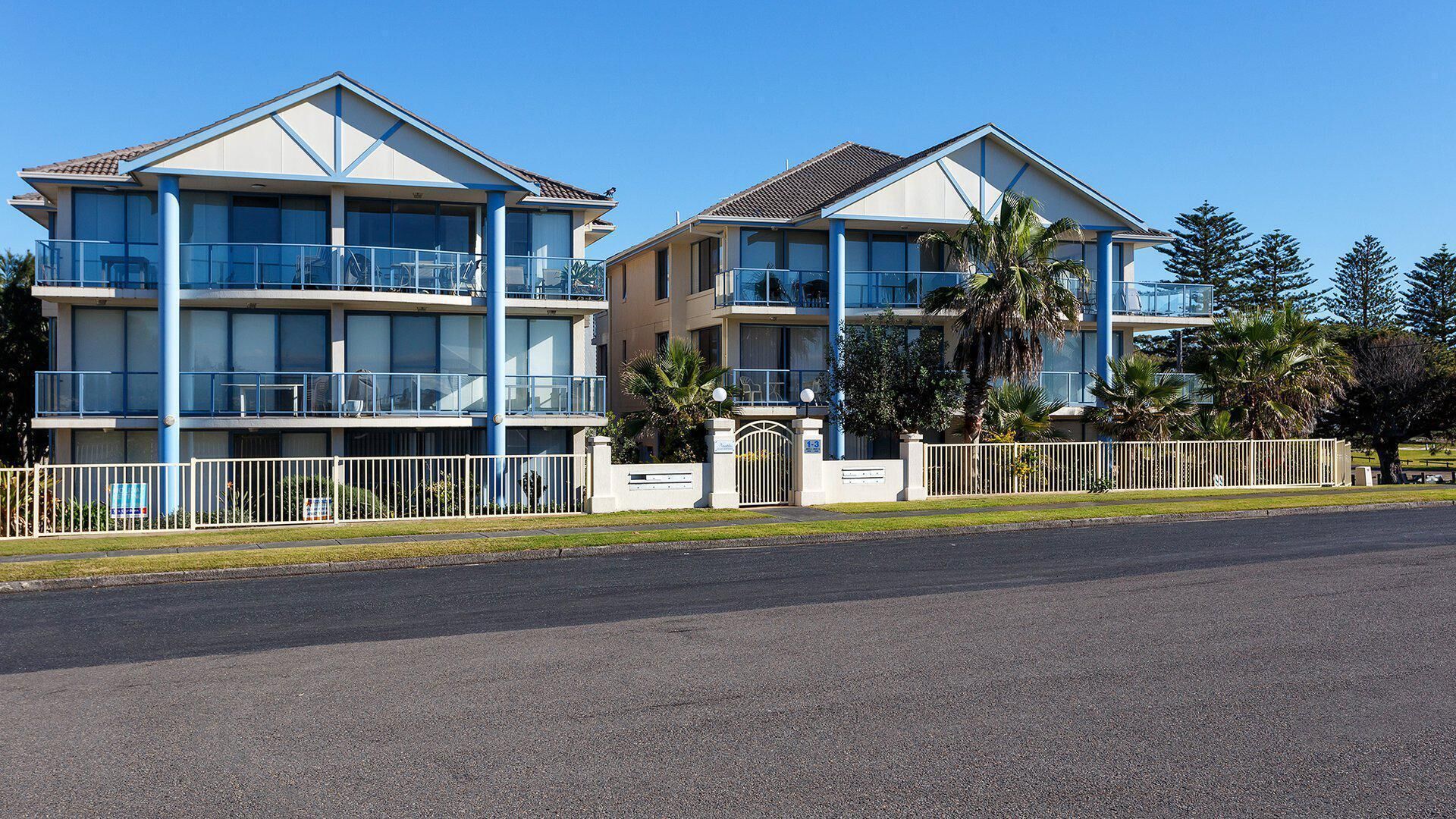 A two-story hotel with balconies, a gated entrance, and a parking lot.