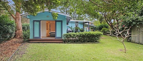 A small, single-story house with a front porch and a visible bedroom.
