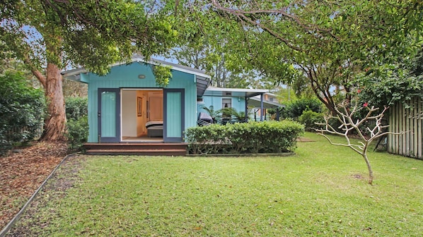 A small, single-story house with a front porch and a visible bedroom.