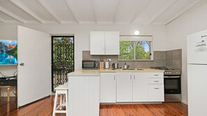 A modern kitchen with white cabinets, a built-in oven, and a window overlooking greenery. - Enjoy the soothing sea breeze (Hawks Nest)