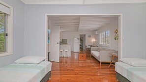 A room with two beds, a kitchenette, a dining area, and a view of the outdoors. - Enjoy the soothing sea breeze (Hawks Nest)