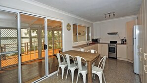 A compact kitchen with a dining area, sliding glass doors leading to a deck, and a small oven.