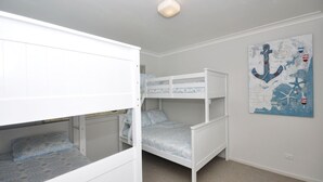 A room with bunk beds, a nautical-themed wall art, and a light switch on the wall.