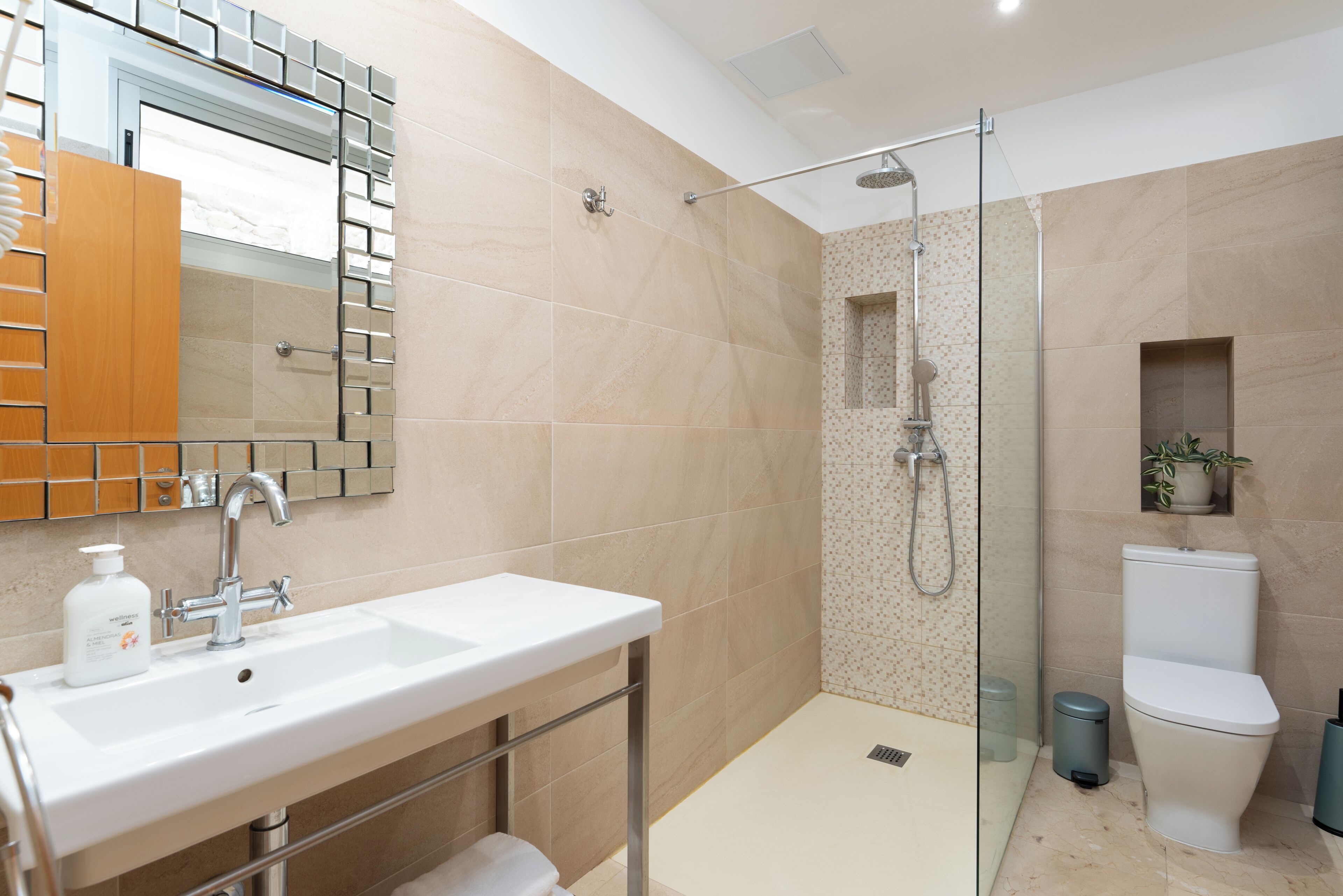 Een moderne badkamer met een douchecabine van glas, een witte wastafel en een toilet.