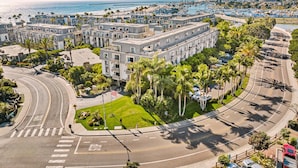A multi-story hotel with a central courtyard, surrounded by a coastal road and beach. - Luxury remodel - Secluded with stunning Ocean views - B301 North Coast Village (Oceanside)
