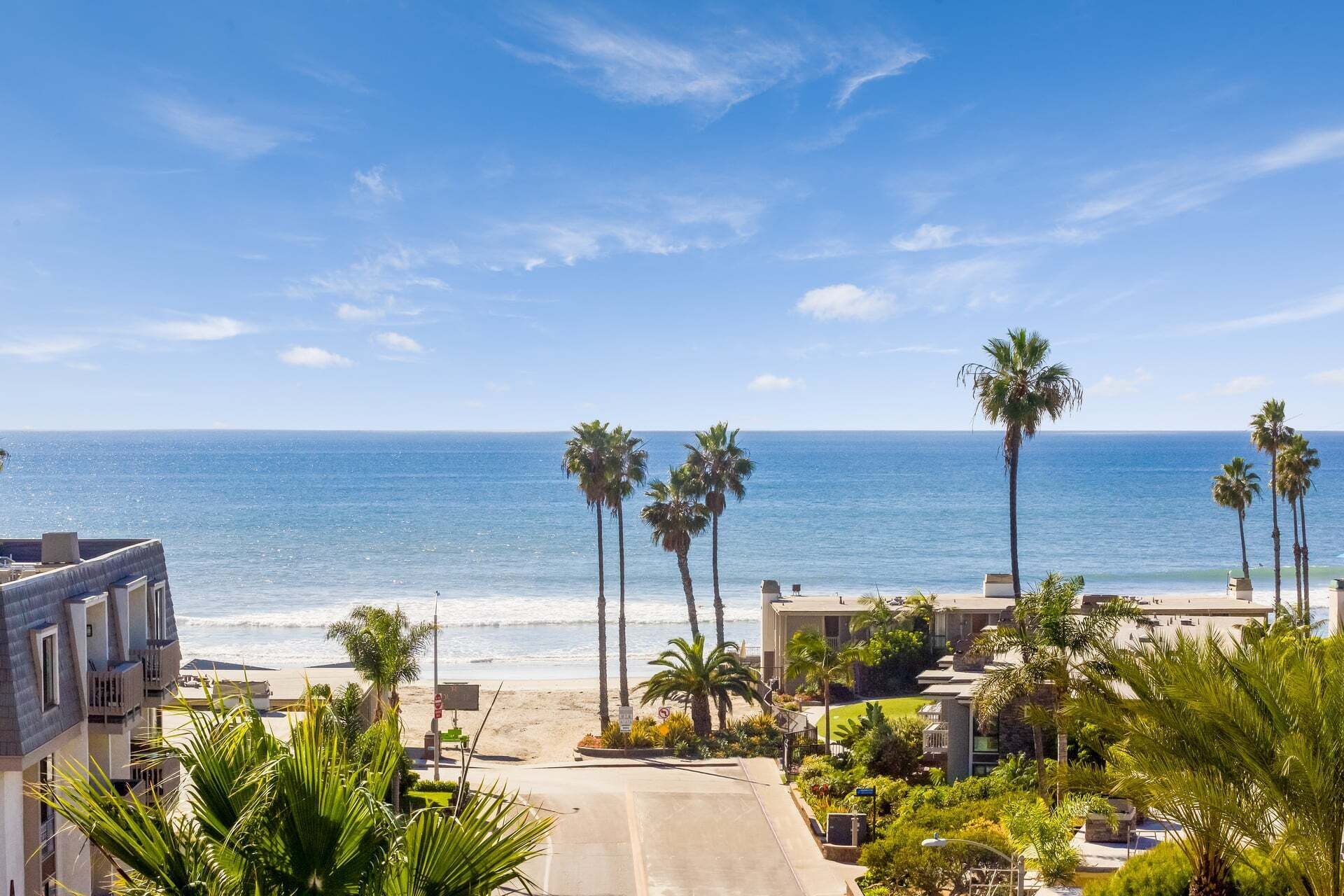 Ein Küstenanwesen mit freiem Blick auf den Ozean, Palmen und einer Straße, die zum Strand führt.