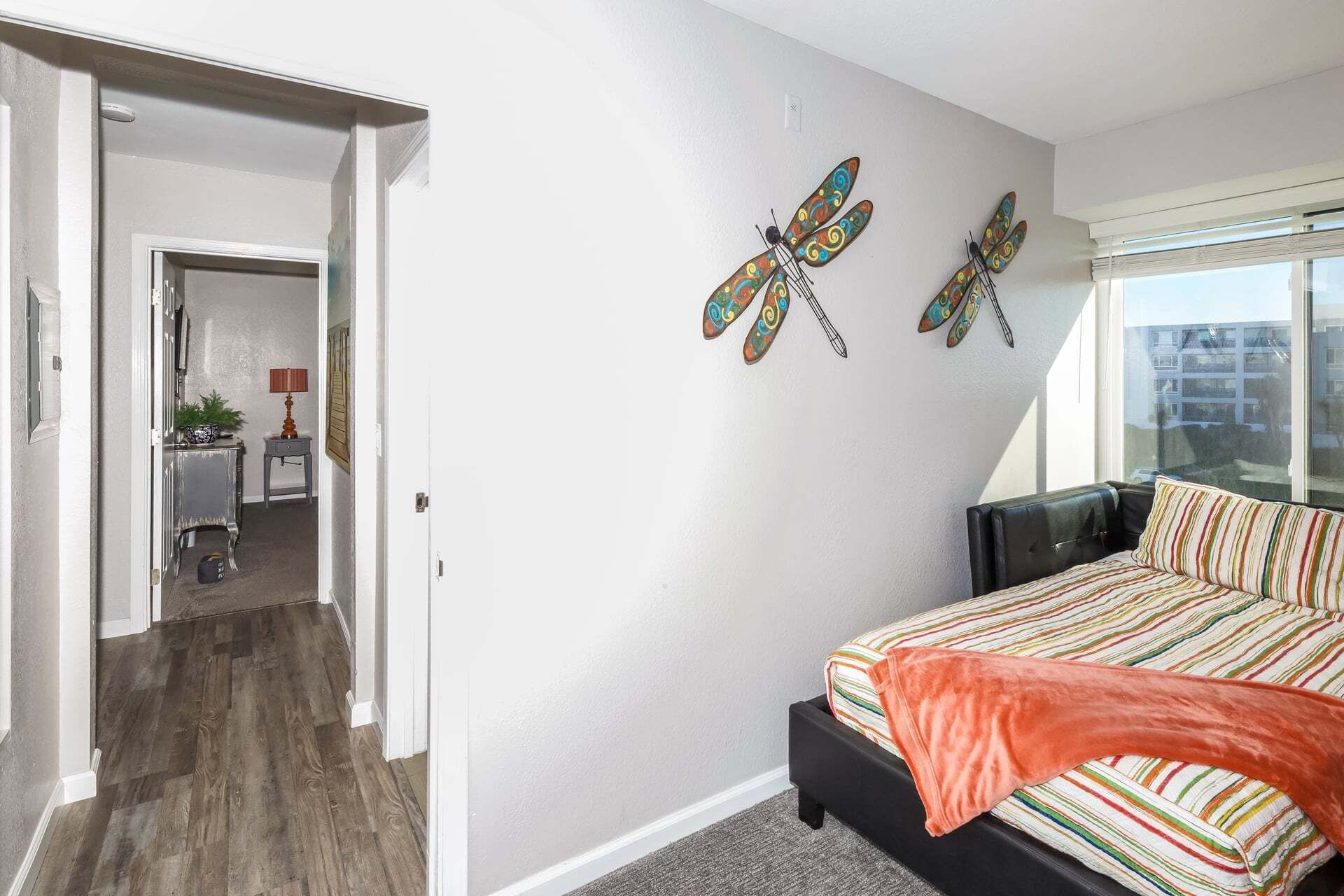 A bedroom with a bed, a window, and a door leading to a hallway.