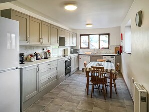 Une cuisine moderne avec un coin repas, comprenant des placards, un réfrigérateur, un four à micro-ondes, un évier et une table à manger avec des chaises.