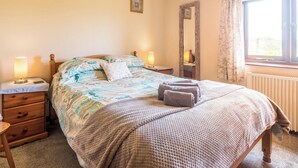 A bedroom with a bed, bedside lamps, a dresser, a mirror, and a window with curtains. - Trewin Court - UK11878 (Holsworthy, near Launceston)