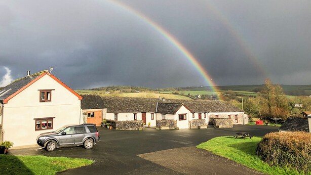 A rural setting with a house, a parked car, and a rainbow. - Trewin Court - UK11878 (Holsworthy, near Launceston)