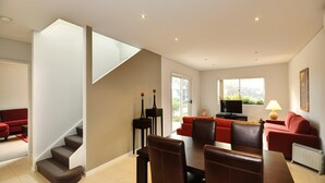 A spacious living area with a staircase, a dining table, and red sofas.