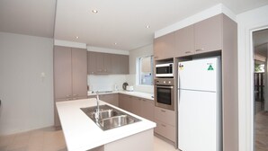 A modern kitchen with stainless steel appliances, a white countertop, and a built-in oven.