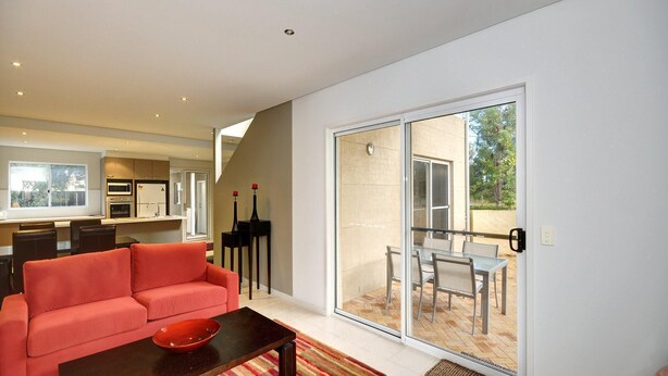 A modern living room with a red sofa, a glass door leading to an outdoor patio with a table and chairs.