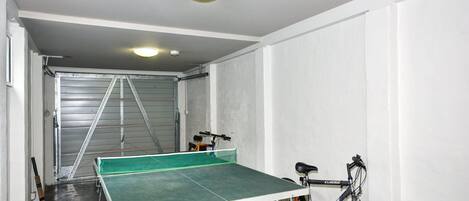 A room with a ping pong table, a bicycle, and a metal gate.