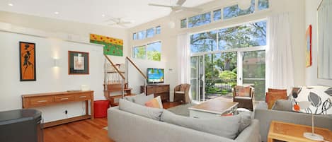 A spacious living room with a large sofa, a television, and a dining area with a table and chairs.