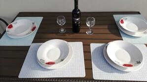 A dining table set with white plates, two wine glasses, and a bottle of wine. - Casa Marina apartment  kontokali  (Kontokali)