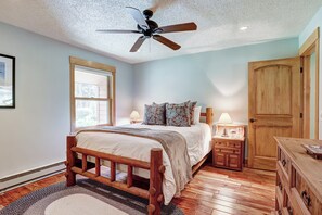 Ein Schlafzimmer mit einem Holzbett, einem Deckenventilator, einem Nachttisch mit Lampe und einem Holzschrank.