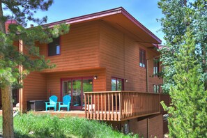 Eine zweistöckige Holzhütte mit einer Terrasse und Sitzbereich im Freien.