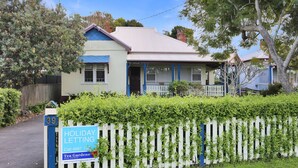 A two-story house with a blue and white exterior, a front porch, and a white picket fence.
