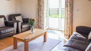 A living room with two leather sofas, a wooden coffee table, and a vase with flowers.