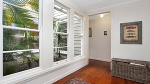 A hallway with a large window, a wicker basket, and a framed fish picture on the wall. - Beach Shack - close to the beach (Hawks Nest)