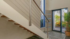 Un escalier moderne avec des rampes en métal et des marches en bois menant à une porte en verre.