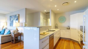 A modern kitchen with white cabinets, a sink, and a clock on the wall. - Myall River Magic - well-appointed townhouse overlooking the Myall River (Tea Gardens)