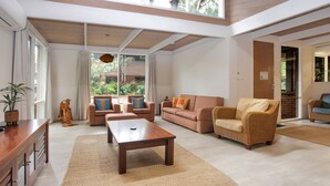 A spacious living room with a wooden coffee table, two sofas, and a wicker armchair. - Sandy Shores - Hawks Nest Holiday Home (Hawks Nest)