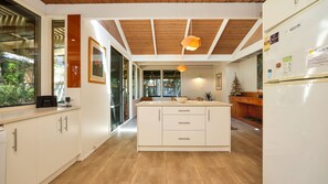 Een moderne keuken met een centraal eiland, houten balken in het plafond en uitzicht door de ramen.