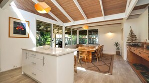 Une cuisine moderne dotée d’un îlot central, de poutres en bois au plafond et de grandes fenêtres.