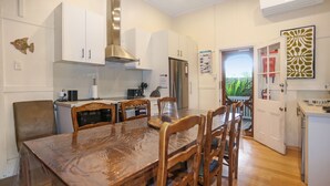 Una cocina moderna con armarios blancos, electrodomésticos de acero inoxidable y un comedor con mesa y sillas de madera.
