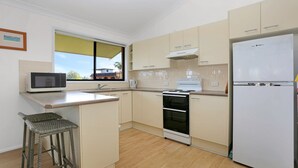 Une cuisine moderne équipée d’un four à micro-ondes, d’une cuisinière et d’un réfrigérateur. Une fenêtre offre une vue sur l’extérieur.