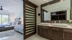 A modern bathroom with a large mirror, dual sinks, and dark cabinetry. - swim up At Mareazul Resort 2 bedrooms 2 bathrooms short walk to beach (Playa del Carmen)