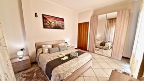 A bedroom with a large bed, a nightstand, a mirror, and a painting on the wall. - Modern apartment between Milan and Como (Cogliate)