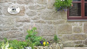 Un cottage in pietra con un cartello che riporta 'Cowslip Cottage'.