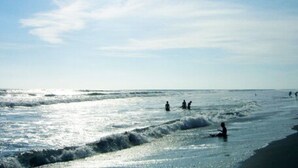 Una playa con gente nadando y caminando por la orilla.