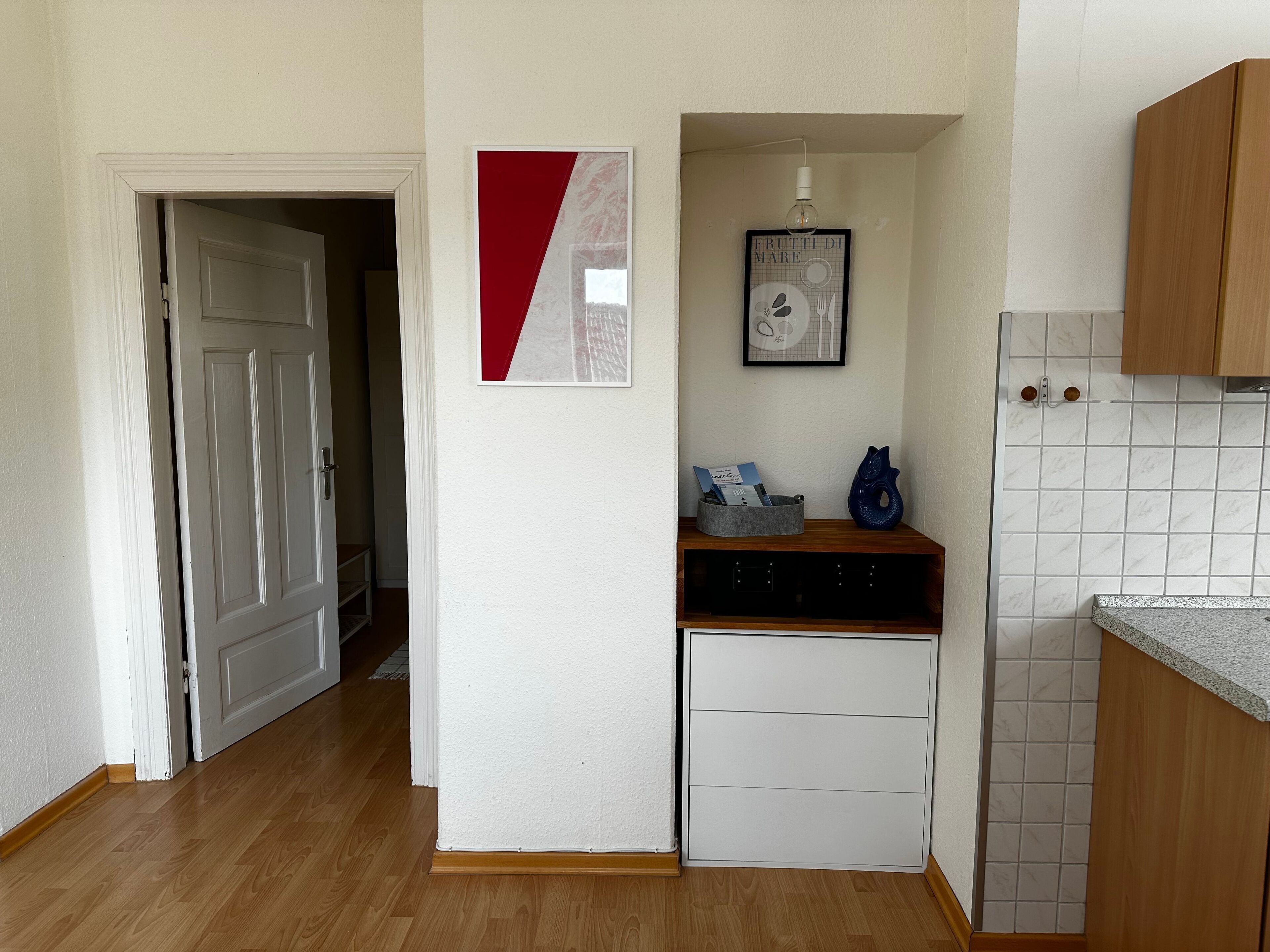 A compact kitchen with white cabinets, a countertop, and a small refrigerator.
