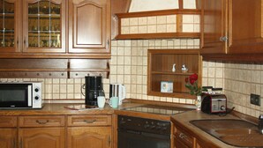 Een keuken met houten kastjes, een magnetron, een koffiezetapparaat, een broodrooster en een vaatwasser.
