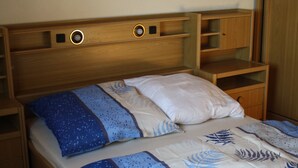 Een bed met een houten hoofdbord, twee nachtkastjes en een bedtafel.