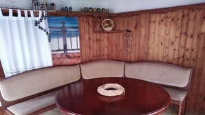 Een kamer met houten lambrisering, een ronde houten tafel en een gebogen bank met beklede zitplaatsen.
