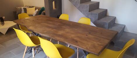 A dining area with a long wooden table and yellow chairs, a staircase, and a modern interior design.