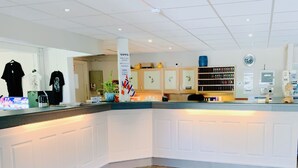 A hotel reception area with a counter, a clock, and a plant. - Hallingskarvet Fjellstue AS (Hol)