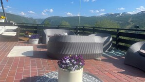 A terrace with wicker furniture and potted plants, overlooking a mountainous landscape. - Hallingskarvet Fjellstue AS (Hol)